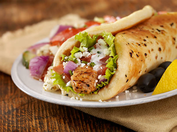 Chicken Souvlaki Wrap Chicken Souvlaki Pita Wrap with Lettuce, Tomatoes, Red Onions, Feta Cheese, Tzatziki Sauce and a Side of Greek Salad -Photographed on Hasselblad H3D-39mb Camera flatbread stock pictures, royalty-free photos & images
