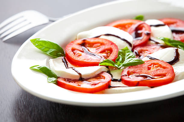 Plate of Layered Tomato And Mozzarella with Balsamic Glaze Closeup Selective Focus closeup of a plate of tomatoes mozzarella and basil with a balsamic glaze balsamic vinegar stock pictures, royalty-free photos & images