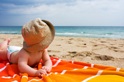 Cute baby on the beach looking at the ocen