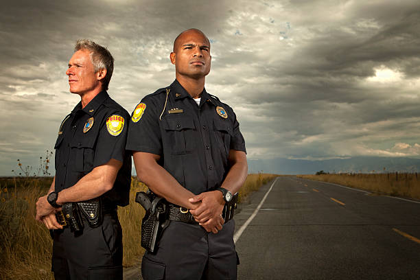 Two police officers standing on quiet road Police Officers. This stock image has a horizontal composition. Arm Badge Create by me, Gold Chest Emblem Custom Ordered Generic security guard photos stock pictures, royalty-free photos & images