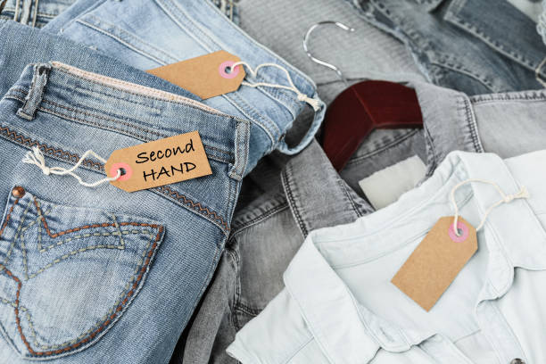 istock Stack of blue jeans, shirts and tag with inscription second hand 1715941735