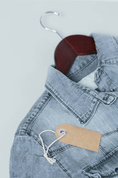 istock Gray denim shirt with empty tags on hanger on white background 1715941741
