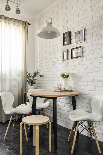 Bouquet of tulips in interior of the kitchen in Scandinavian style with white furniture and a dining table. All photos in photo frames on whall made by me.