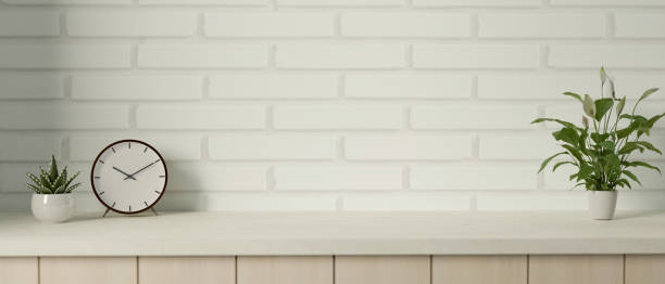 istock Copy space on a minimalist tabletop against white brick wall with an alarm clock and potted plants. 1716018208