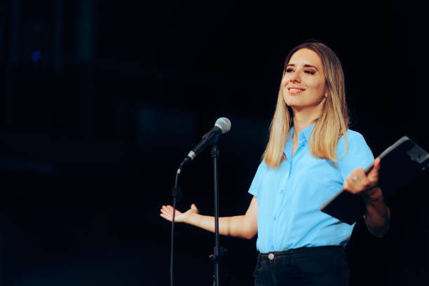 istock Public Speaker Holding a Clipboard Taking on a Microphone ion a Stage 1716054748