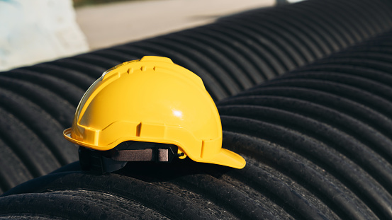 Yellow engineer hard safety helmet hat on Circular water Pipe. Construction and Oil Natural Gas and fuels Transport concept.
