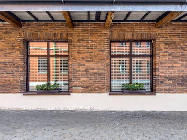 istock two windows with flower pots on red brick wall. renovated old building facade. 1716192460