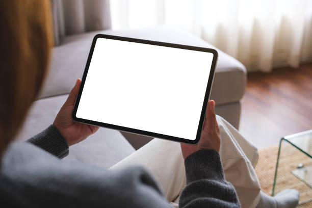 istock Mockup image of a woman holding digital tablet with blank desktop screen while sitting on a sofa at home 1716203714