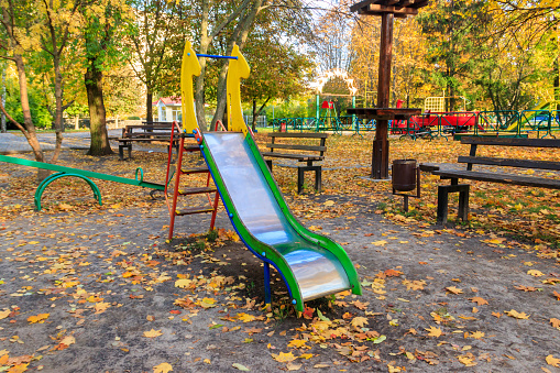 Colorful playground equipment for children in public park at autumn