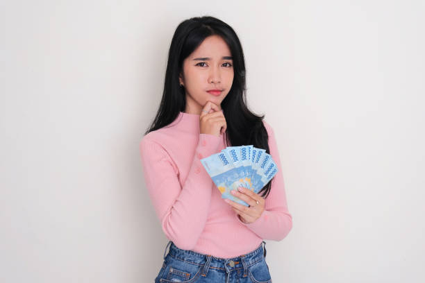 istock Asian young woman thinking something with serious expression while holding money 1716266463