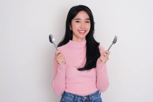 istock Asian young woman smiling while holding a spoon and fork 1716266475
