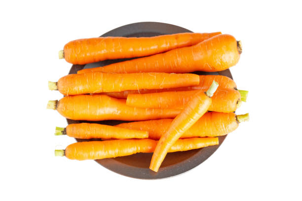 świeże małe marchewki z łodygą na glinianym naczyniu. surowa organiczna pomarańczowa domowa marchew warzywna z usuniętymi zielonymi liśćmi - carrot isolated bunch baby carrot zdjęcia i obrazy z banku zdjęć