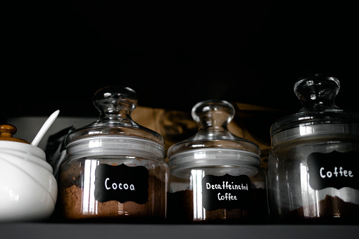 Several types of ground coffee in glass containers are on the shelf. Breakfast coffee concept. Process of making coffee at home.