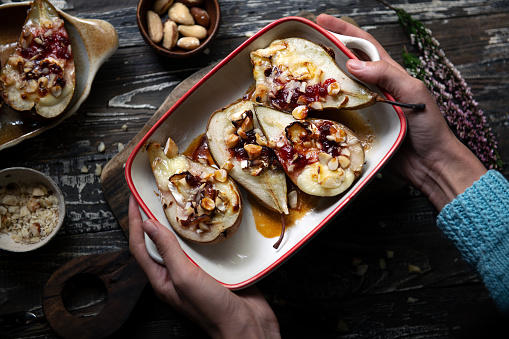 Pears baked with cheese, walnuts, jam and honey are served on a plate.
