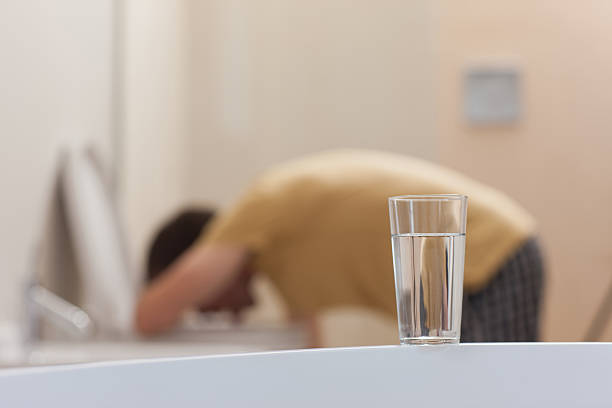 kuvapankkikuvat ja rojaltivapaat kuvat aiheesta glass of dissolving medicine with vomiting man in background - hangover