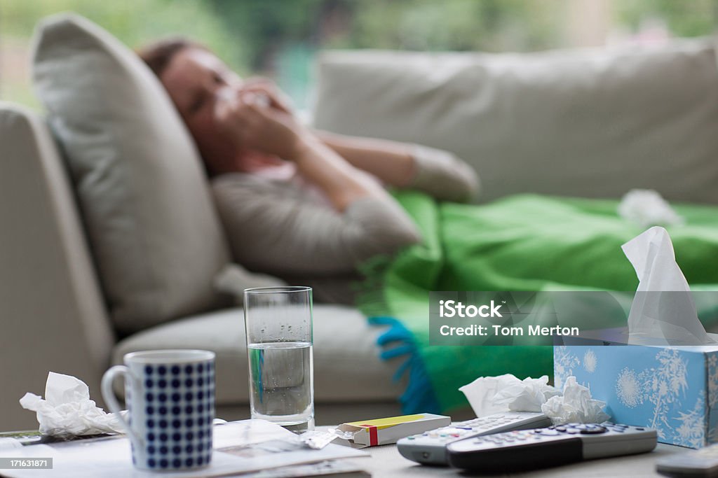 Sick woman laying on sofa blowing nose  Cold And Flu Stock Photo