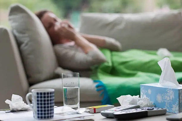Photo of Sick woman laying on sofa blowing nose