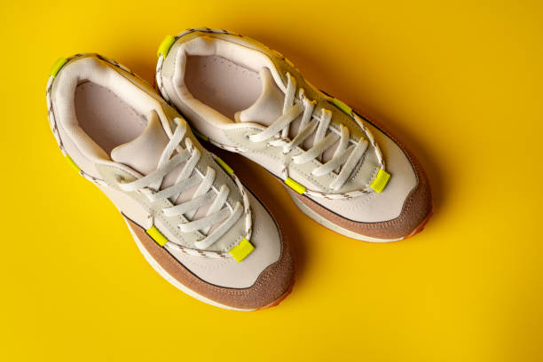 istock Beige sport running shoes on yellow studio background 1716350234