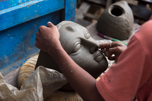 An unknown artist creating clay face of Goddess Durga with use of selective focus