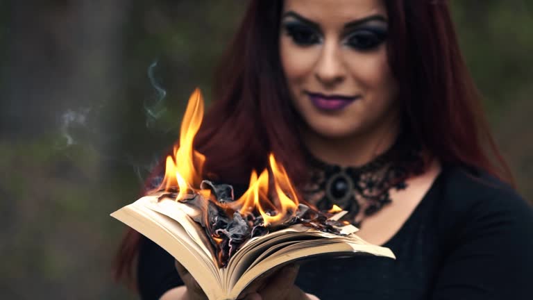 Young Gothic Woman Holding A Burning Book In The Forest