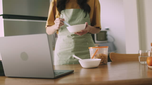 A woman learning to make yogurt from an online course at home.