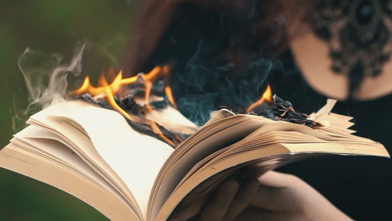 Young Gothic Woman Holding A Burning Book In The Forest