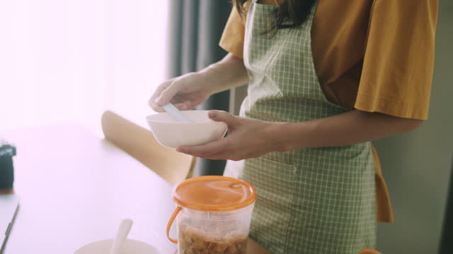 A young woman learning to make yogurt from an online course at home.