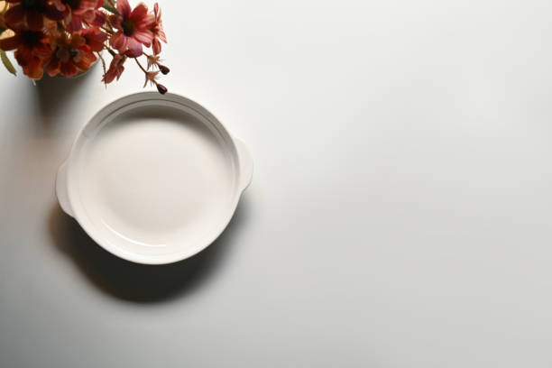 white clay pot with a closed lid on a yellow background, top view