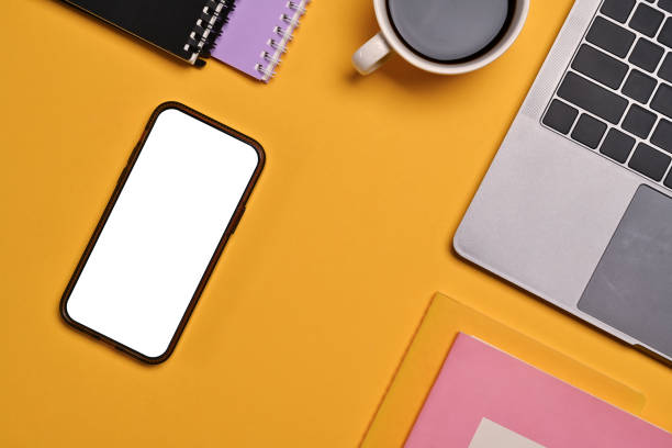 istock Flat lay, top view smartphone with blank screen, laptop, coffee mug and notebook on yellow background 1716437925