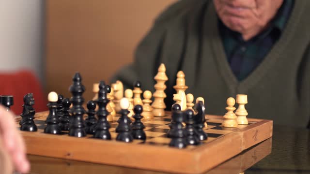 Senior Man And His Grandson Playing Chess At Home