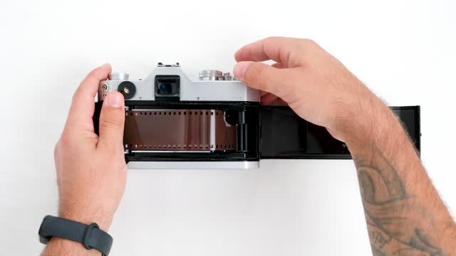 A man is loading 35mm film into an old-fashioned vintage camera