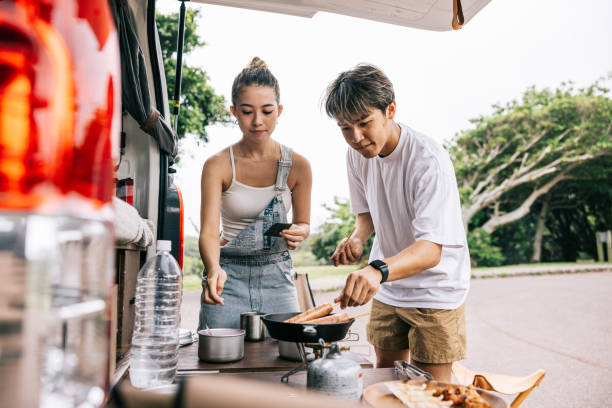 istock Happy Japanese couple cooking dinner behind their van 1716460154