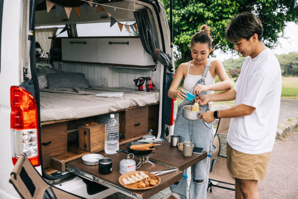 istock Happy Japanese couple cooking dinner behind their van 1716460158