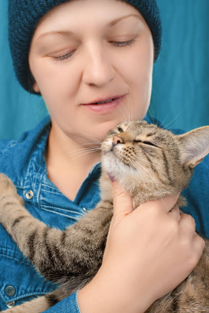 istock Caucasian woman hugs and strokes a tabby cat. Front view. 1716474492