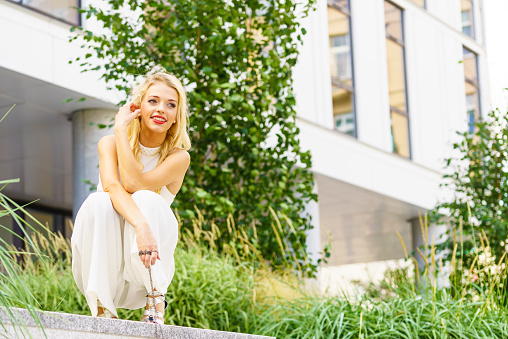 Elegant fashionable woman presenting trendy urban outfit. White crop top and trousers culottes. Outdoor photo session