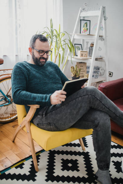 istock Man in living room with digital tablet 1716508539