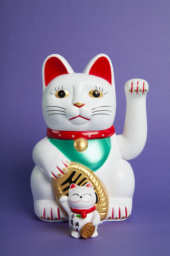 a couple mother and baby of Maneki-neko plastic cat, Symbolizing luck and wealth, on a pop and colorful background. Minimal trendy color still life photography