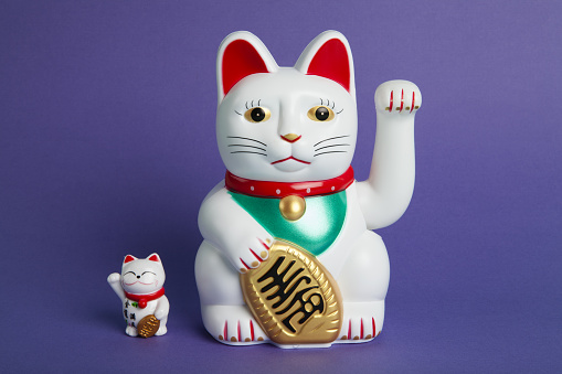 a couple mother and baby of Maneki-neko plastic cat, Symbolizing luck and wealth, on a pop and colorful background. Minimal trendy color still life photography