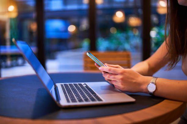 istock Modern female using phone and laptop for remotely working, social networking and online browsing in a cafe 1716516091