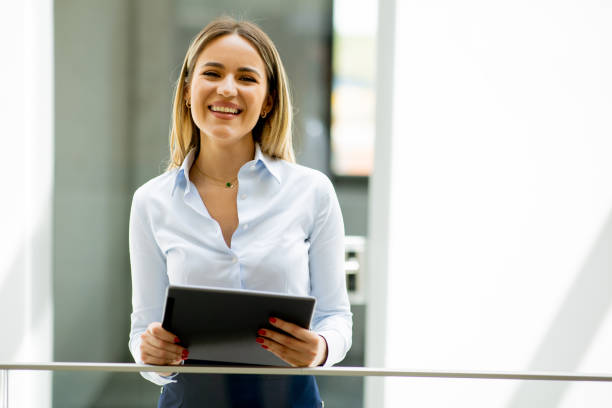 istock Young woman with digital tablet standing in the modern office hallway 1716533880
