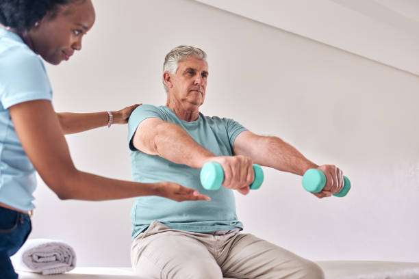 istock Physiotherapy, exercise and old man with dumbbell for wellness and muscle training on bed with woman in room. Healthcare, physiotherapist and senior with workout for healing help, support and fitness 1716536521