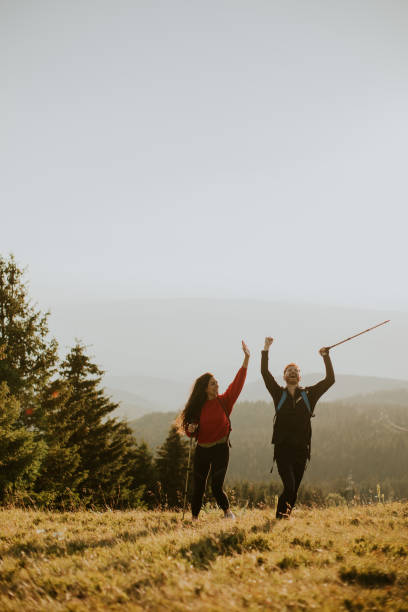 istock Smiling couple walking with backpacks over green hills 1716565256