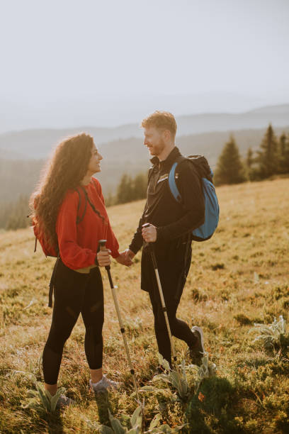 istock Smiling couple walking with backpacks over green hills 1716565259