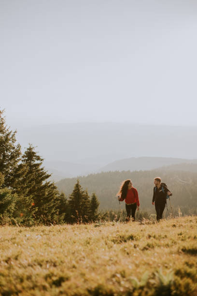 istock Smiling couple walking with backpacks over green hills 1716565262