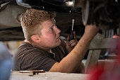 Young auto mechanic repairs a broken car in a car repair shop.