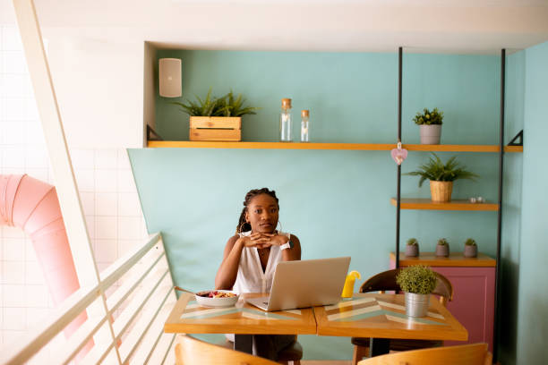 istock Young black woman drinking coffee  while working on laptop in the cafe 1716573410