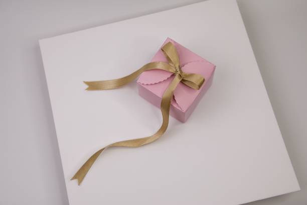 istock Pink gift box with a golden bow displayed on a white background 1716580873