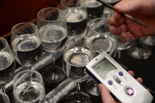 A musician tunes a set of wine glasses partly filled with water to make a full range of notes for a concert performance