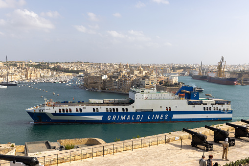 Valetta, Malta - September 23, 2023: Grimaldi Lines cargo ship sailing in the Grand Harbour, photograph taken from the Saluting Battery in Valetta