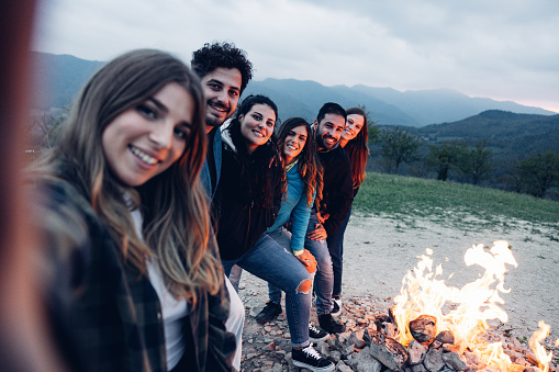 Friends having fun around a fireplace outdoors in Mountain.